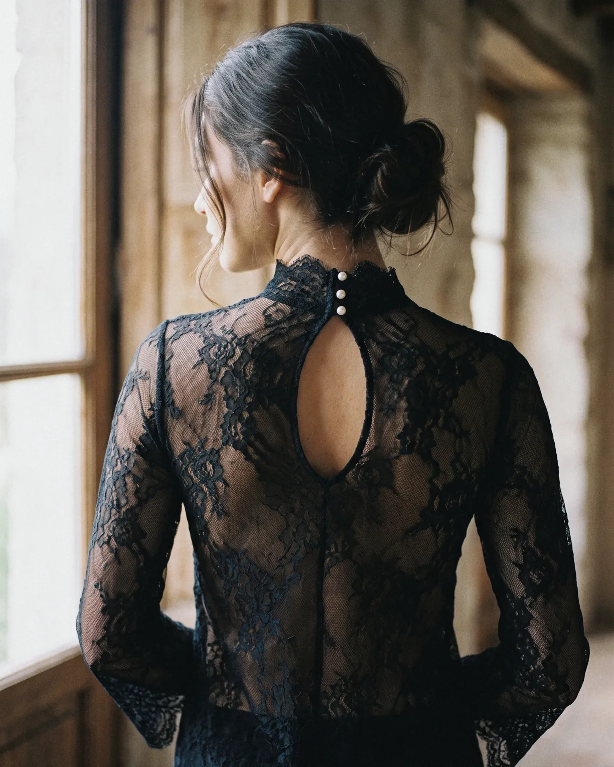 the lace shirt, black floral lace with a high neck, a keyhole and three pearl buttons, worn at a window