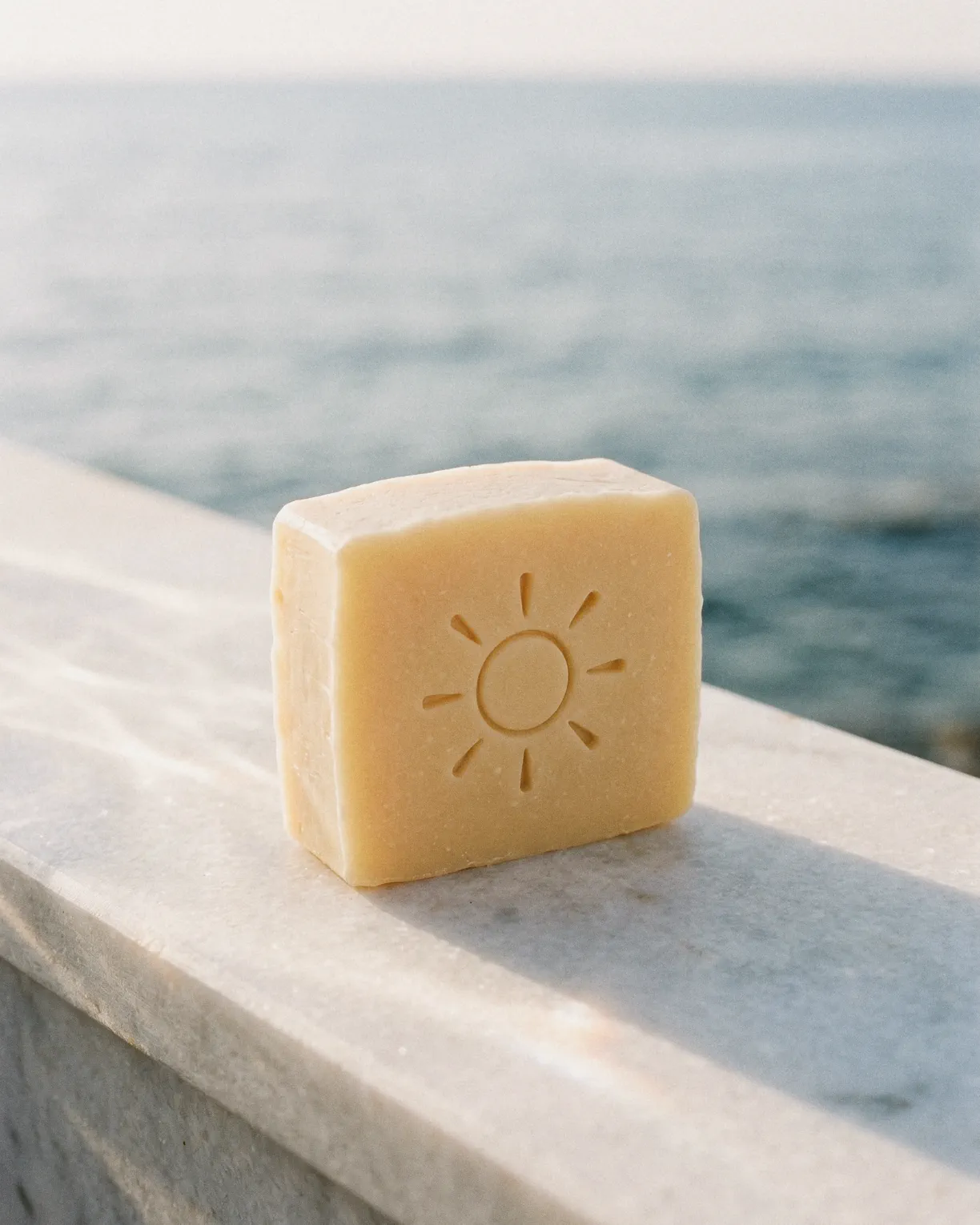 the sun bar up close, its pressed sun facing out, on a white marble ledge above the sea